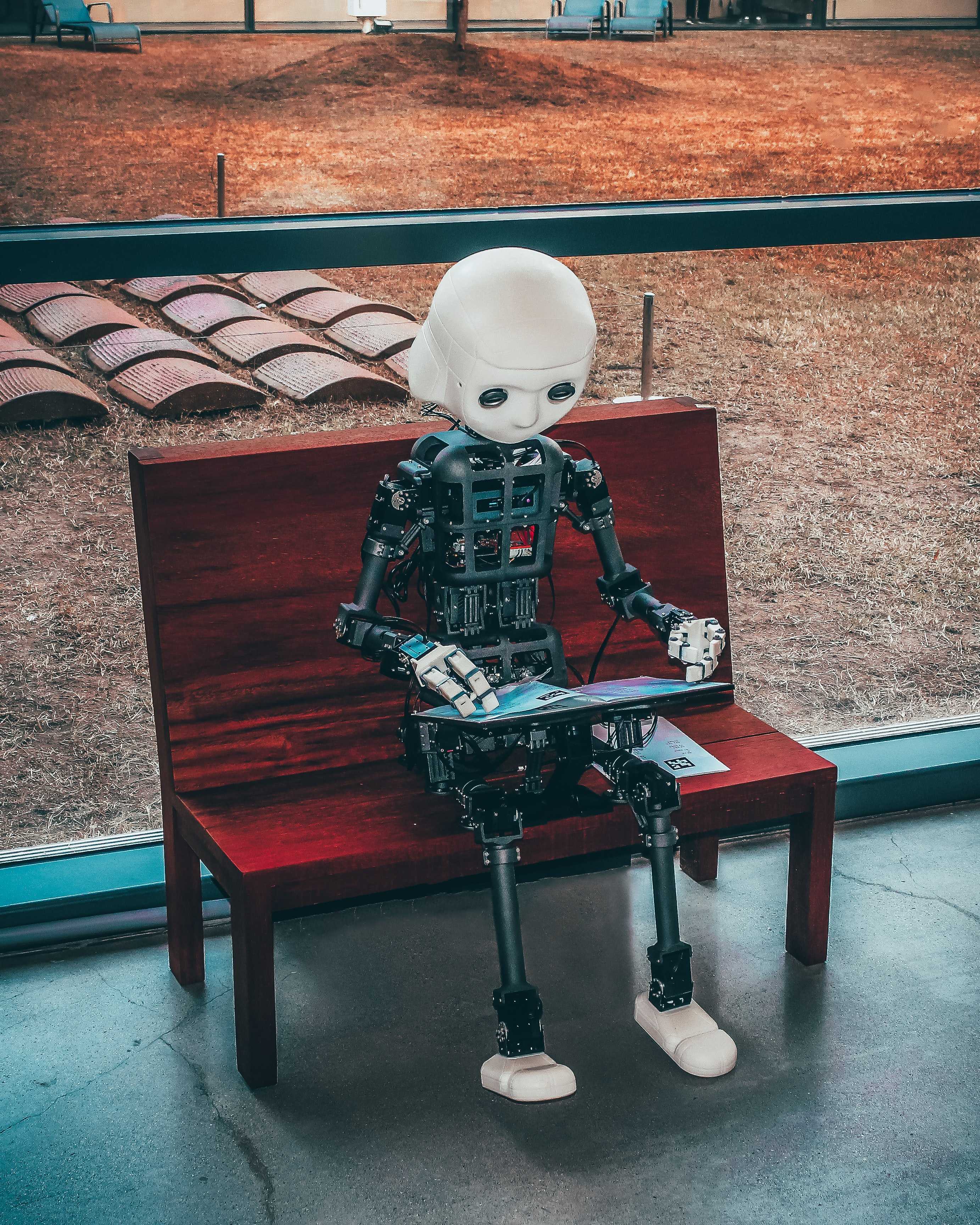 Robot sitting on a bench with a computer